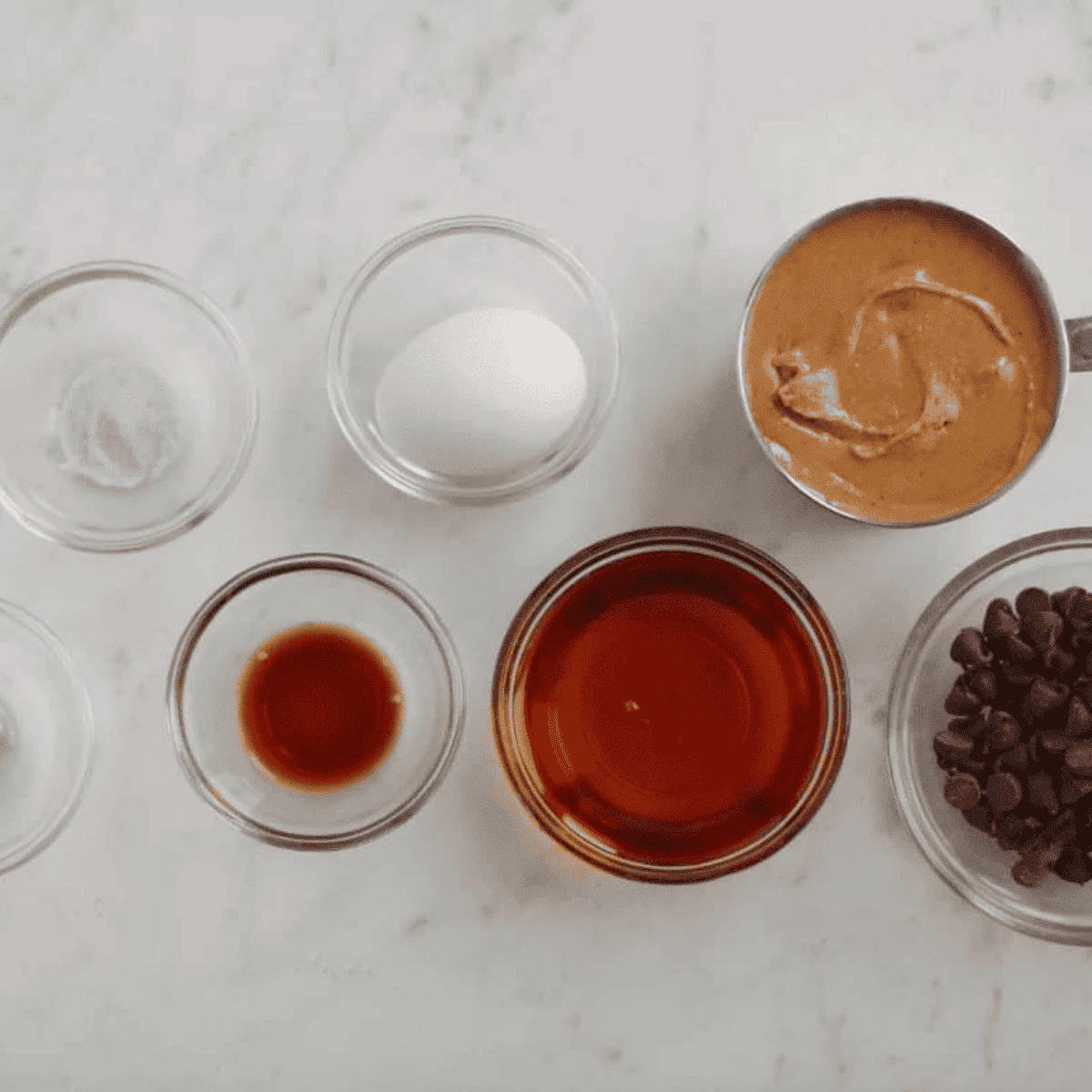 Ingredients for flourless peanut butter blondies: creamy peanut butter, brown sugar, an egg, vanilla, baking soda, salt, and chocolate chips