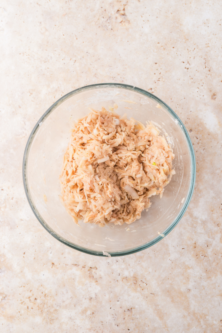 bowl mixing shredded hashbrowns with seasonings and ingredients