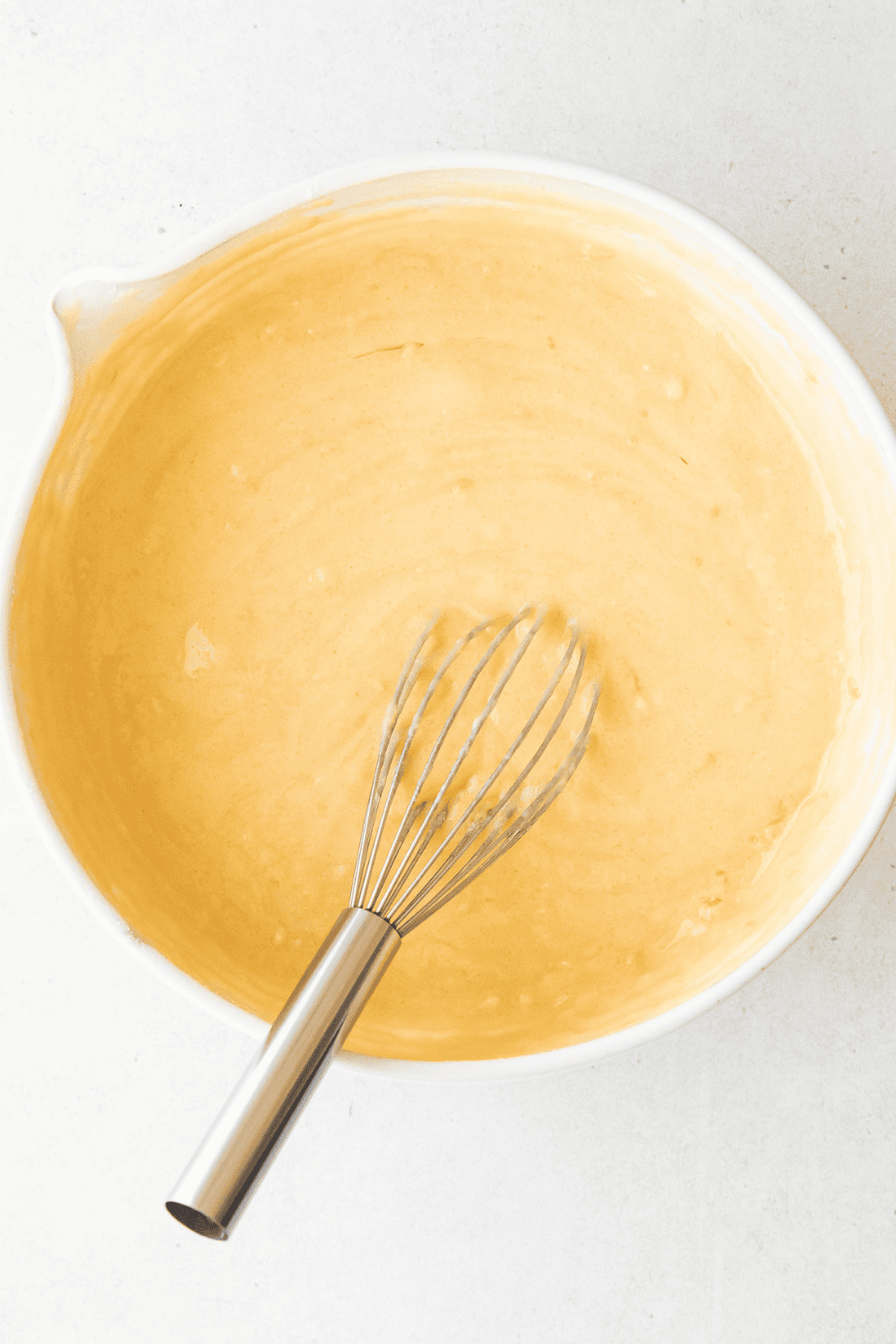 Mixing dry ingredients with sugar, lemon zest, flour, and wet ingredients including butter, eggs, sour cream, milk, and lemon juice to make lemon cupcake batter.