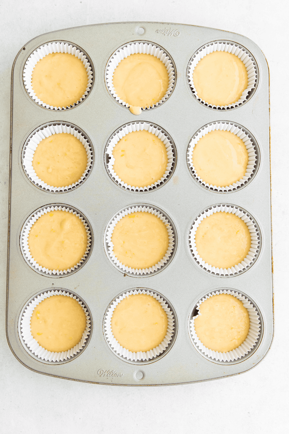Cupcake batter poured into lined muffin tin, air frying at 320°F until fully baked.