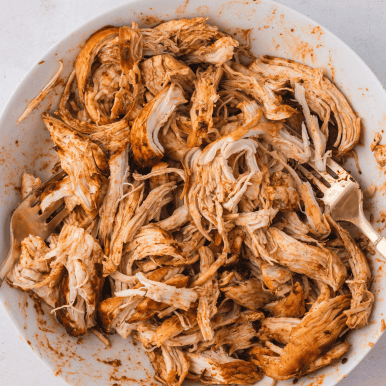 Shredding juicy air fryer chicken with two forks in the pan juices