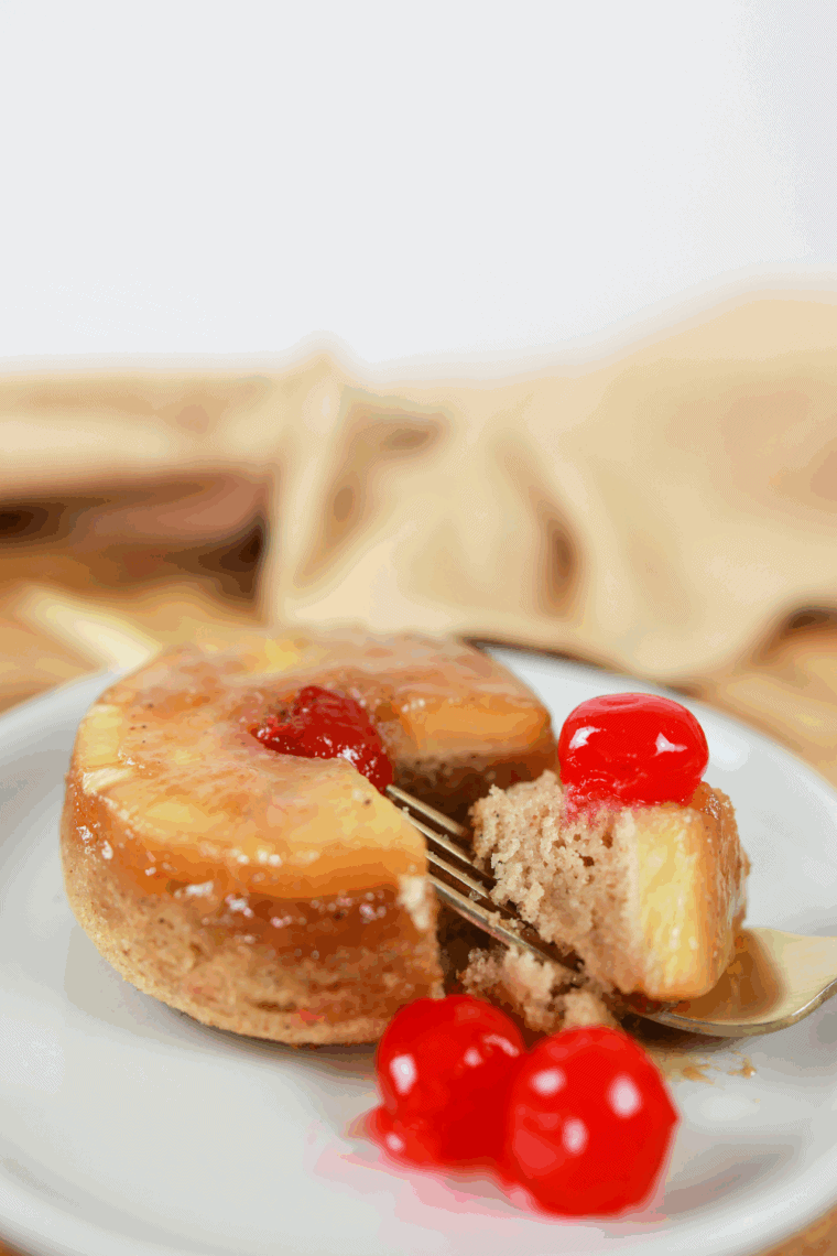 Air fryer pineapple upside-down cake for two served in ramekins with a cherry on top.