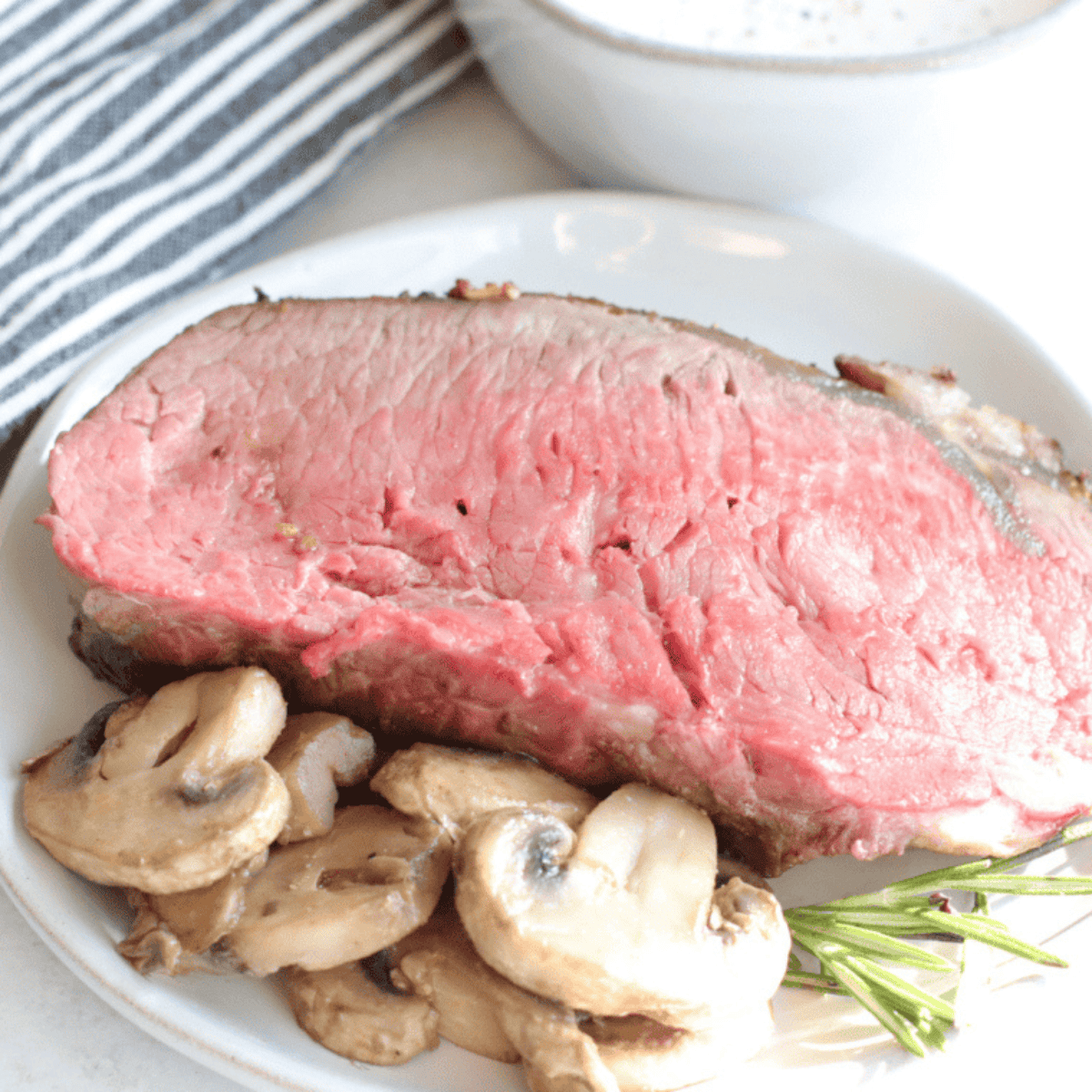 Sliced Air Fryer Prime Rib roast showing a perfect pink medium-rare center, a dark garlic-herb crust, and resting on a cutting board.