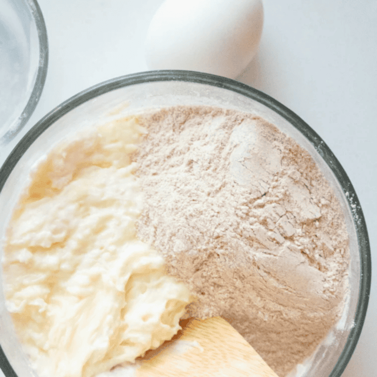 Almond flour and a beaten egg being stirred into melted cheese to form keto fathead dough
