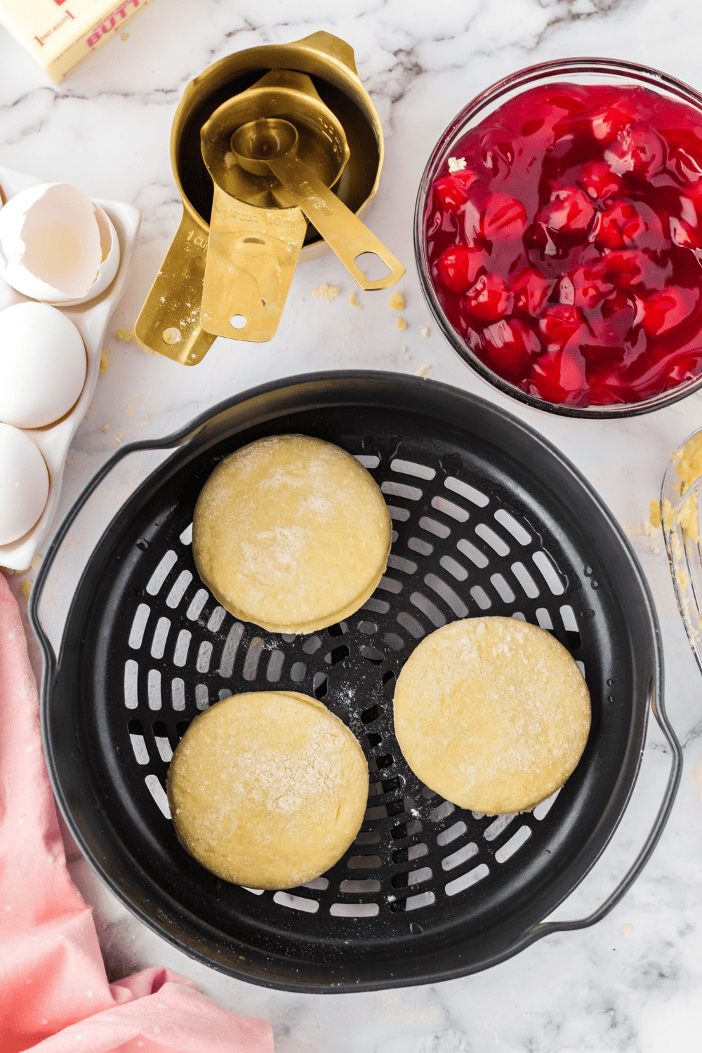 Adding cherry pie filling to the center of the dough circles.