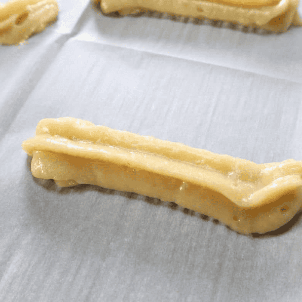 Uncooked churros arranged in an air fryer basket with space between each one before cooking