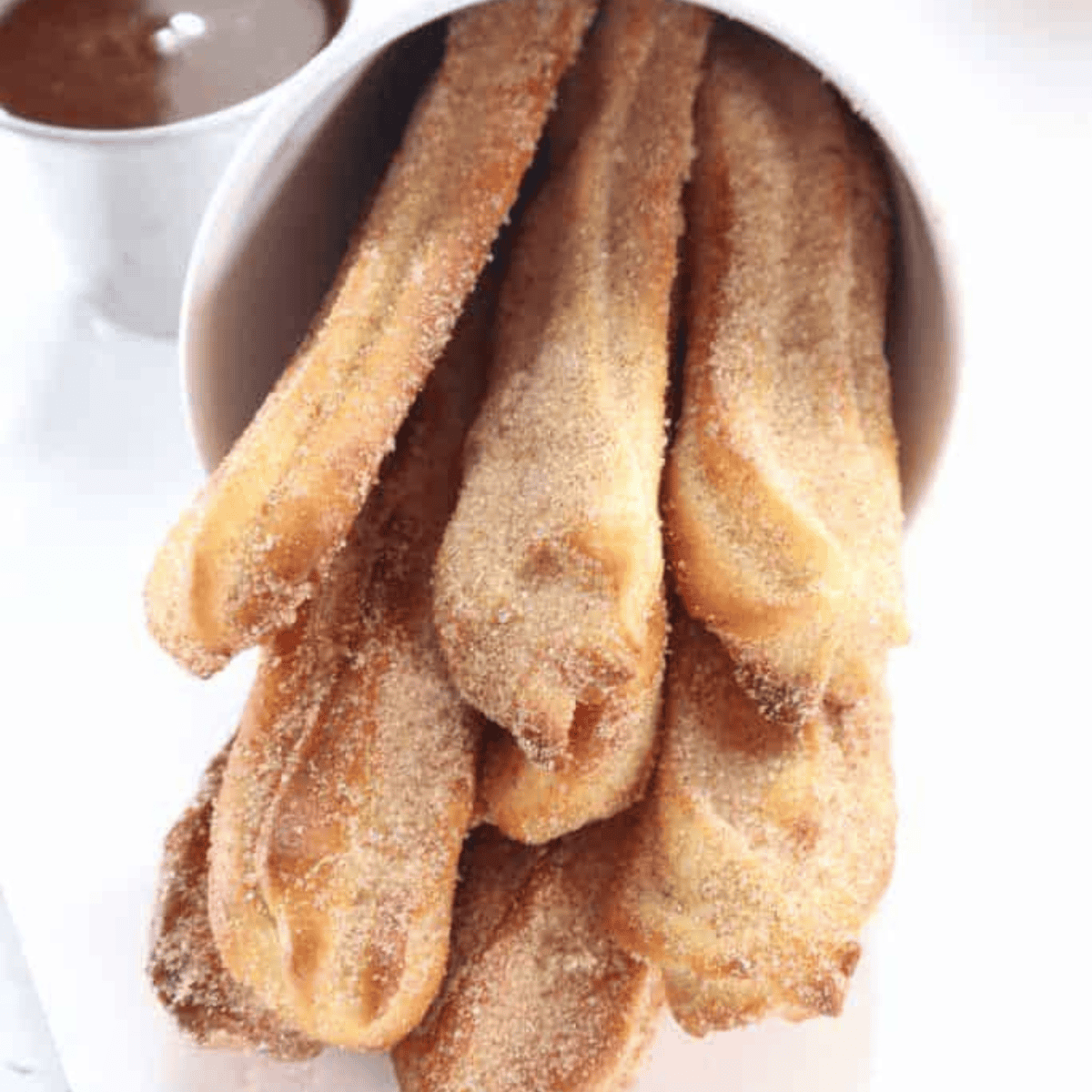 Crispy air fryer churros coated in cinnamon sugar on serving plate