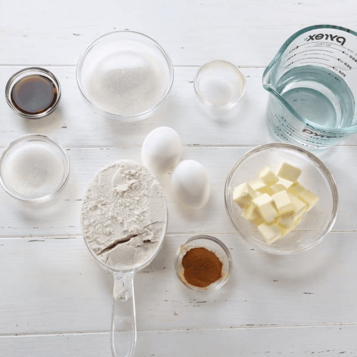 Ingredients for air fryer churros including flour, butter, eggs, sugar, cinnamon, vanilla, and salt arranged on a countertop
