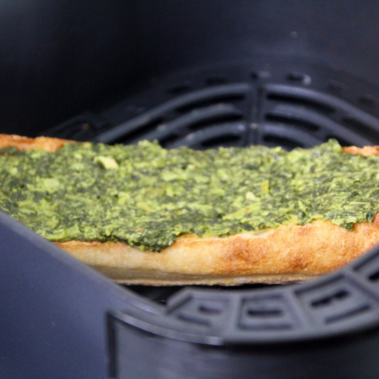 Creamed spinach and melted mozzarella on baguette halves in air fryer.