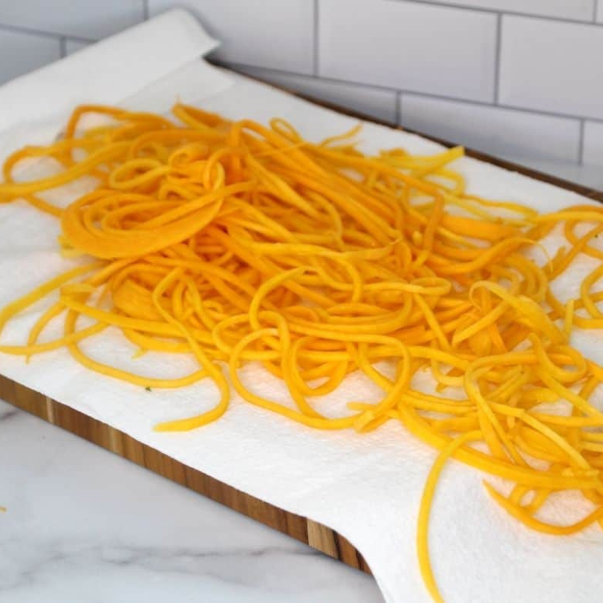 Spiralized butternut squash noodles spread on paper towels to dry