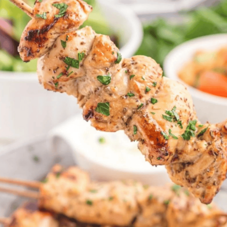 Platter of Air Fryer Greek Chicken Kebabs served with pita bread and vegetables.