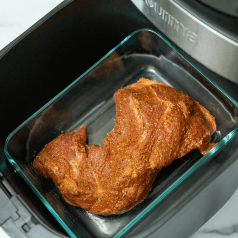 Marinated pork chunks arranged in a single layer in the air fryer basket before cooking