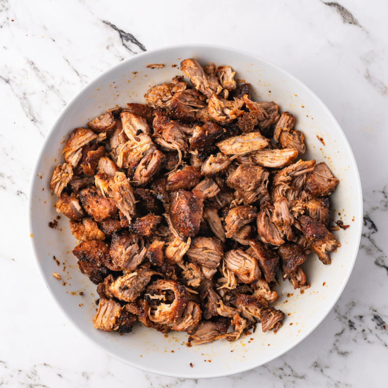 Air fryer pork carnitas shredded with two forks, showing tender meat and crisp browned edges