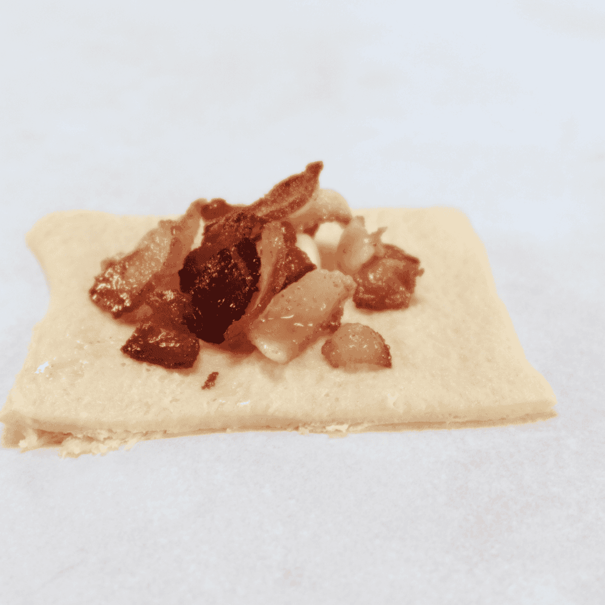 Crescent roll filled with a cube of mozzarella cheese and crumbled bacon, folded and rolled to seal