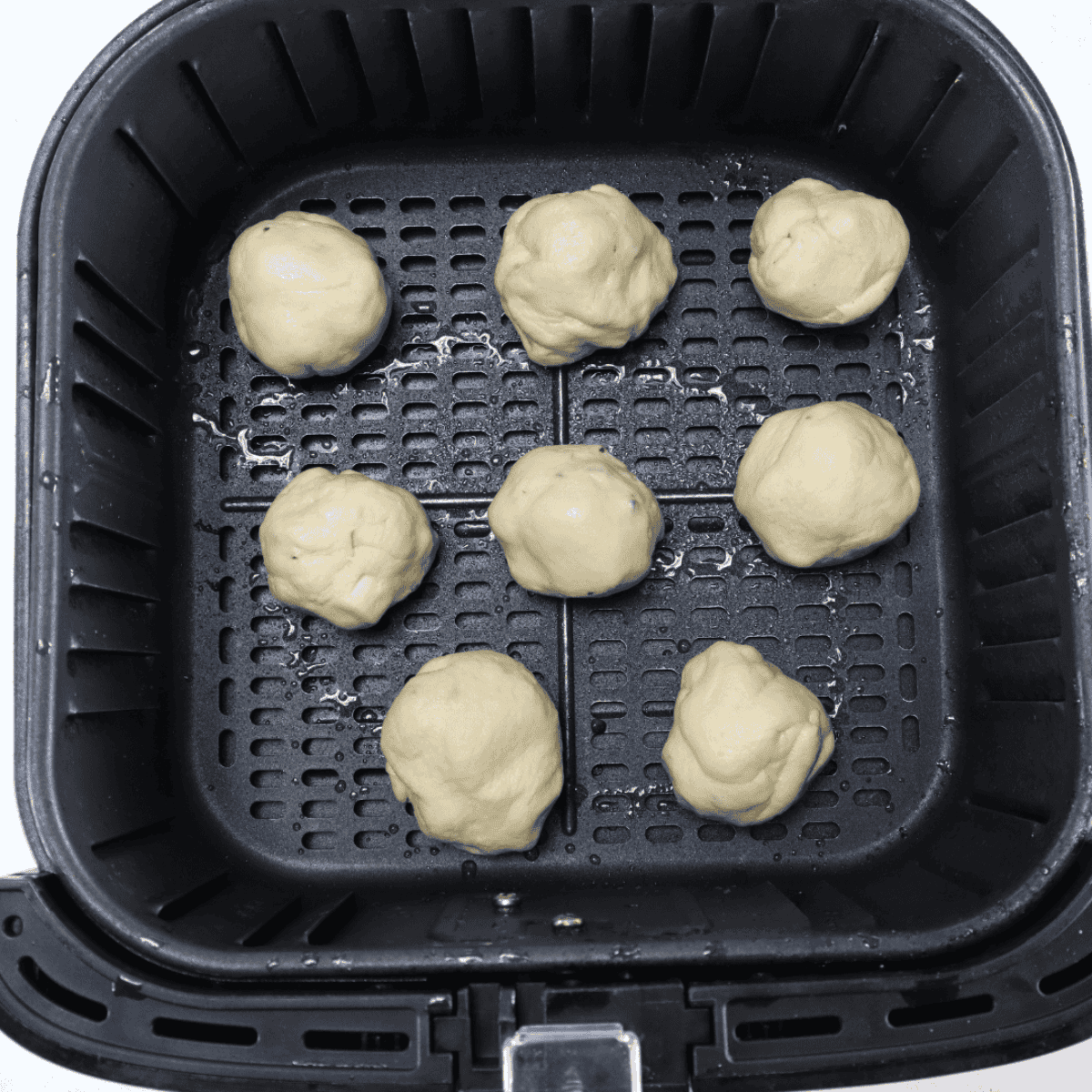 Bacon cheese bombs in an air fryer basket, golden brown, brushed with seasoned butter, ready to serve with pizza sauce or ranch