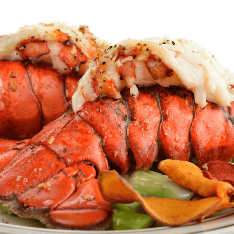 Butter-brushed lobster tail heating in air fryer tray