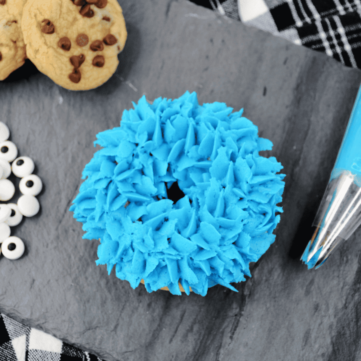 Piping blue frosting onto cooled donuts and adding edible eyes on top