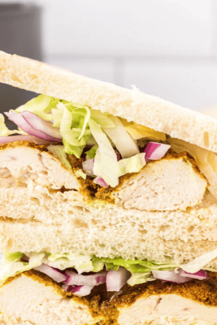Air fryer curried chicken sandwich with golden bread, lettuce, and sliced red onion.