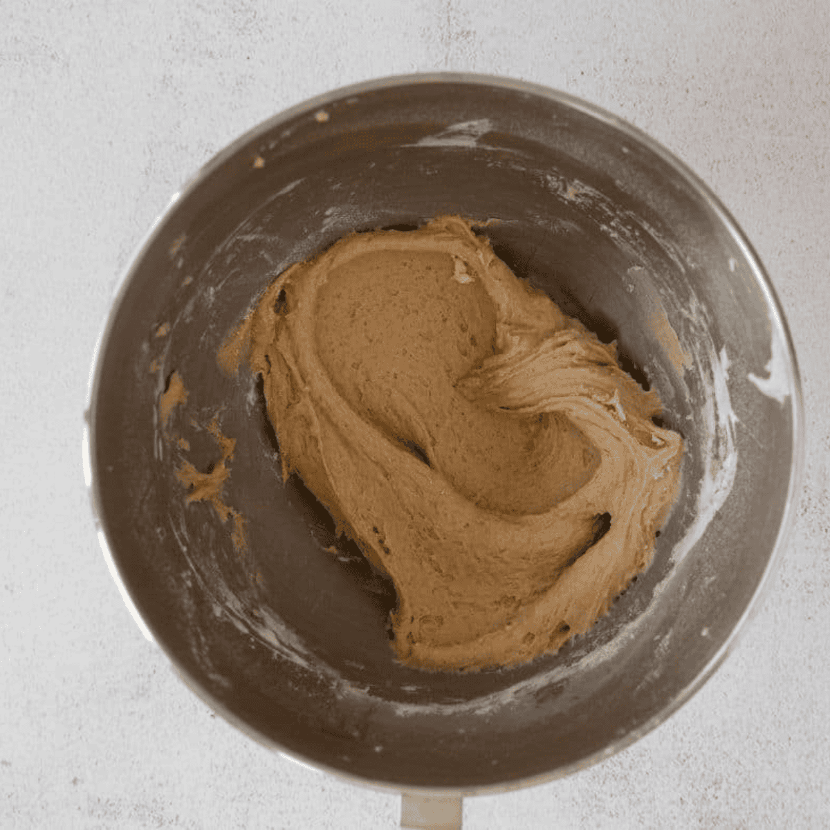 Mixing butter and light brown sugar in a stand mixer with a paddle attachment until light and fluffy to create a soft, tender Amish Apple Cake batter.