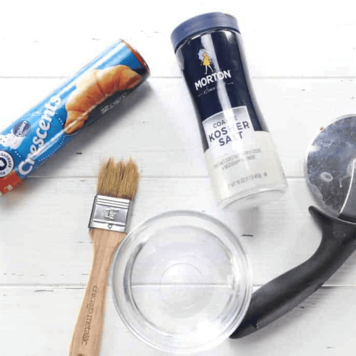Ingredients for air fryer bite-size pretzels on a table: crescent dough, water, and kosher salt