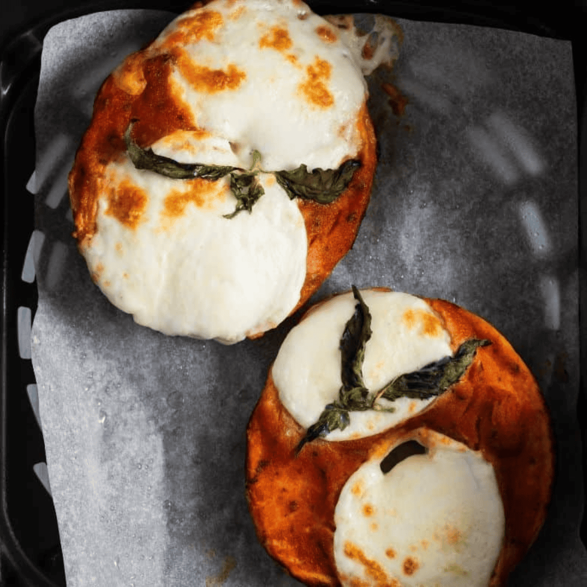 Golden, bubbly Margherita pizza bagels fresh from the air fryer, topped with basil.