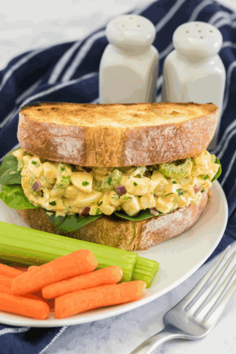 Creamy egg salad with pickles served on toasted bread with lettuce, ready to enjoy as a sandwich or light meal.
