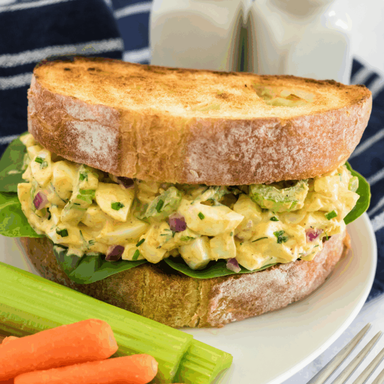 Creamy egg salad with pickles served on toasted bread with lettuce, ready to enjoy as a sandwich or light meal.