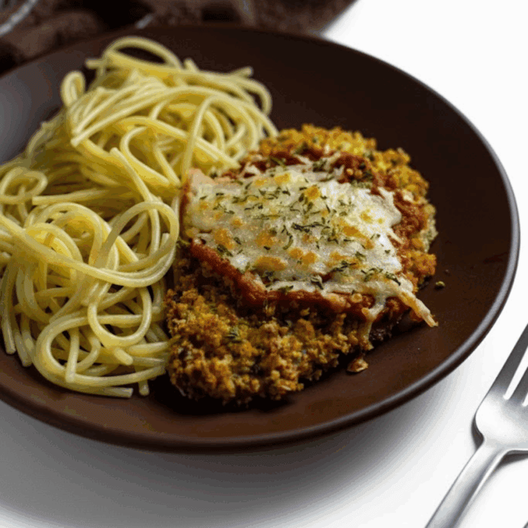 Crispy Easy Air Fryer Veal Parmesan cutlet topped with melted mozzarella cheese and marinara sauce on a plate.