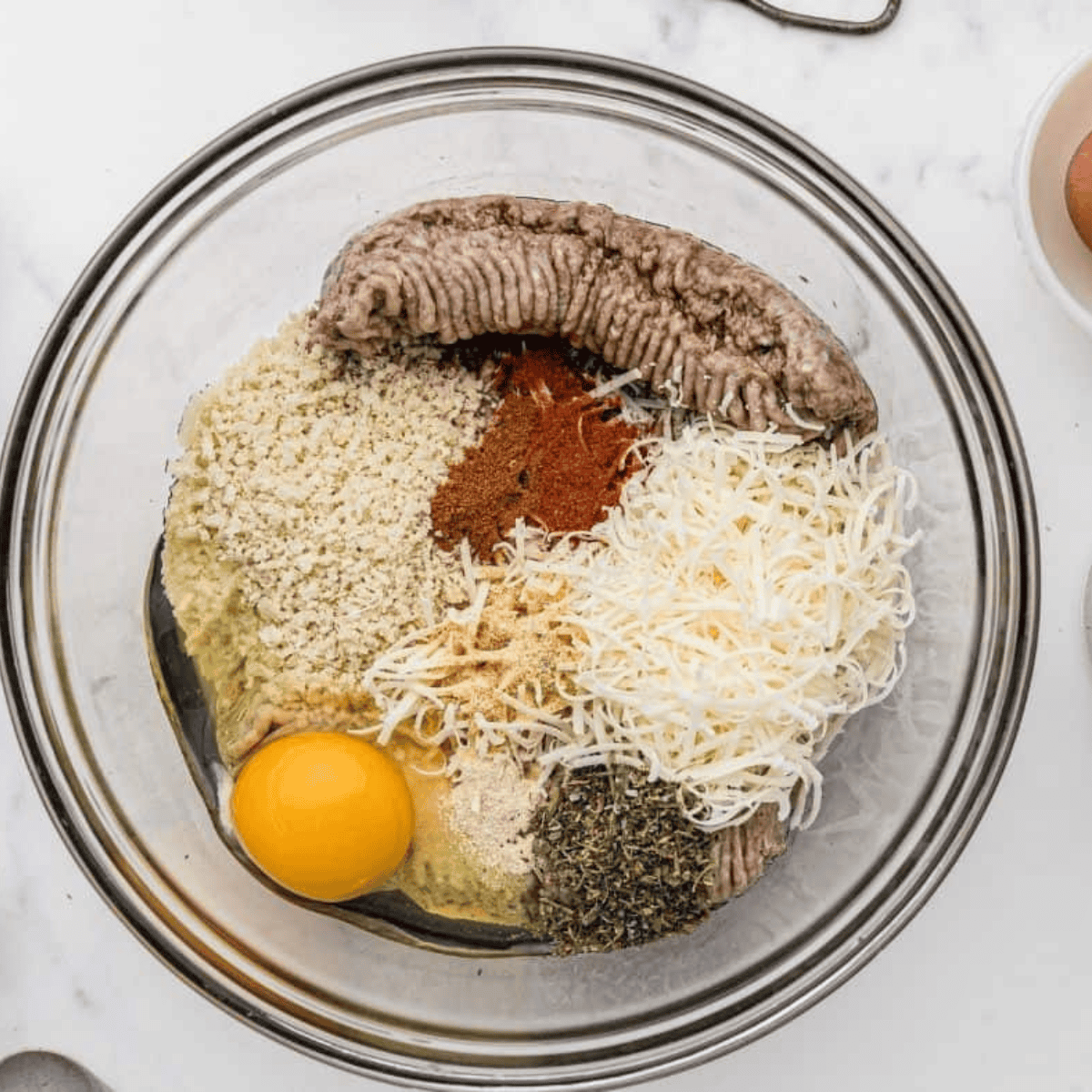 Mixing lean ground turkey, breadcrumbs, grated Parmesan, garlic, parsley, Italian seasoning, salt, pepper, and an egg in a large bowl.