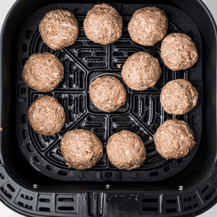Turkey meatballs arranged in a single layer in an air fryer basket, ready to cook at 370°F for even browning.