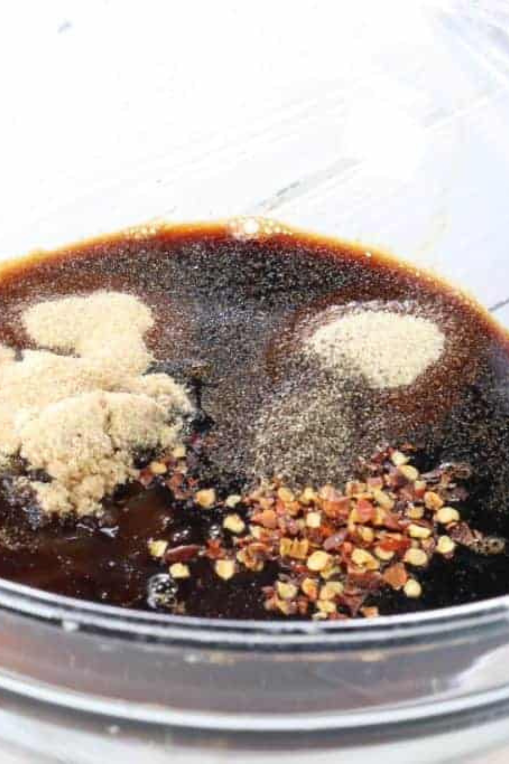 Soy sauce, teriyaki, brown sugar, and seasonings whisked together in a glass bowl for homemade air fryer beef jerky marinade