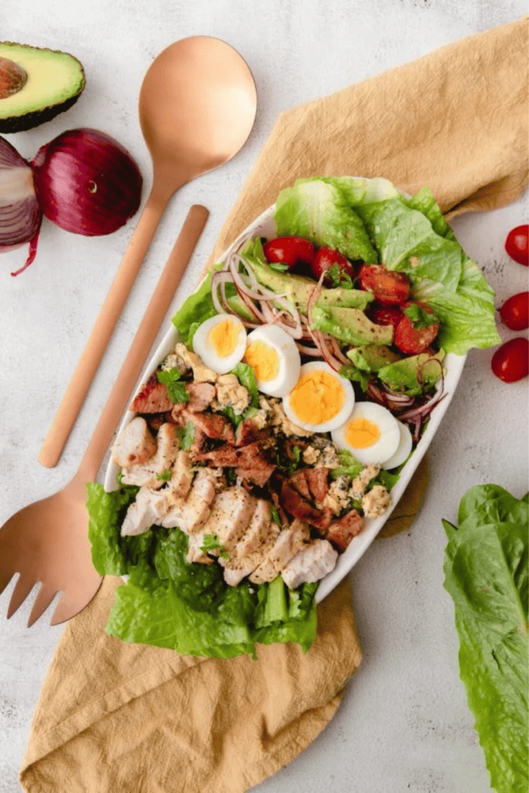 Air fryer Cobb salad plated with sliced chicken, bacon, hard-boiled egg, avocado, cherry tomatoes, and blue cheese