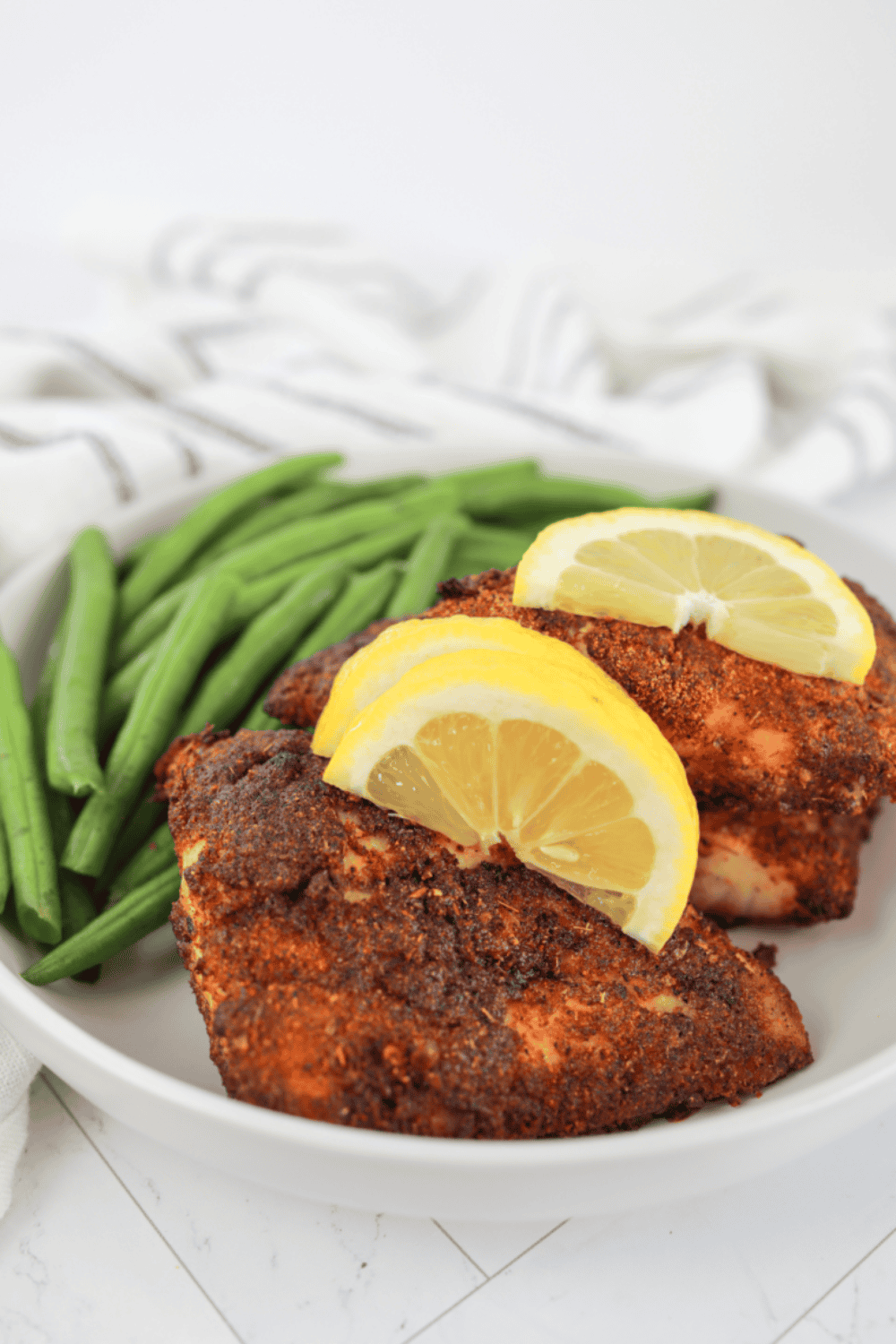 Golden, flaky air fryer red snapper fillet served with lemon wedges and fresh herbs