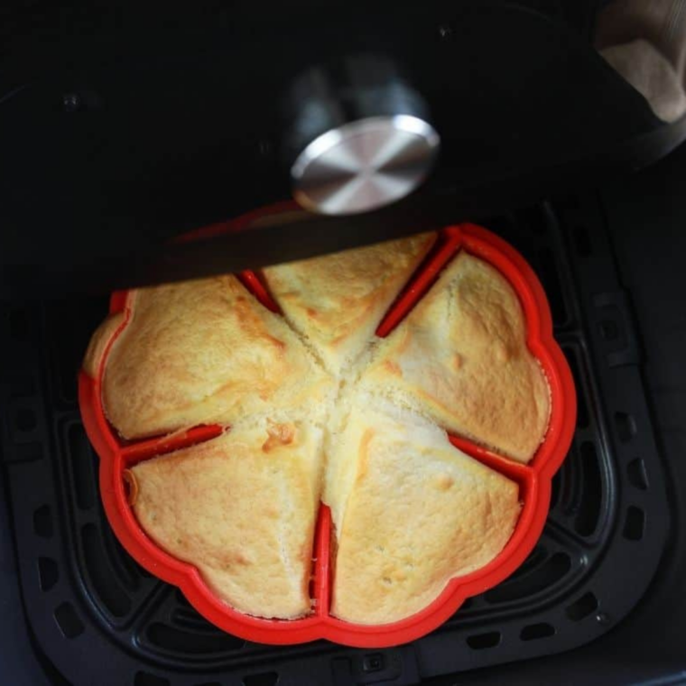 Waffle being cooked in the air fryer and then set in a muffin tin to cool into a bowl shape.