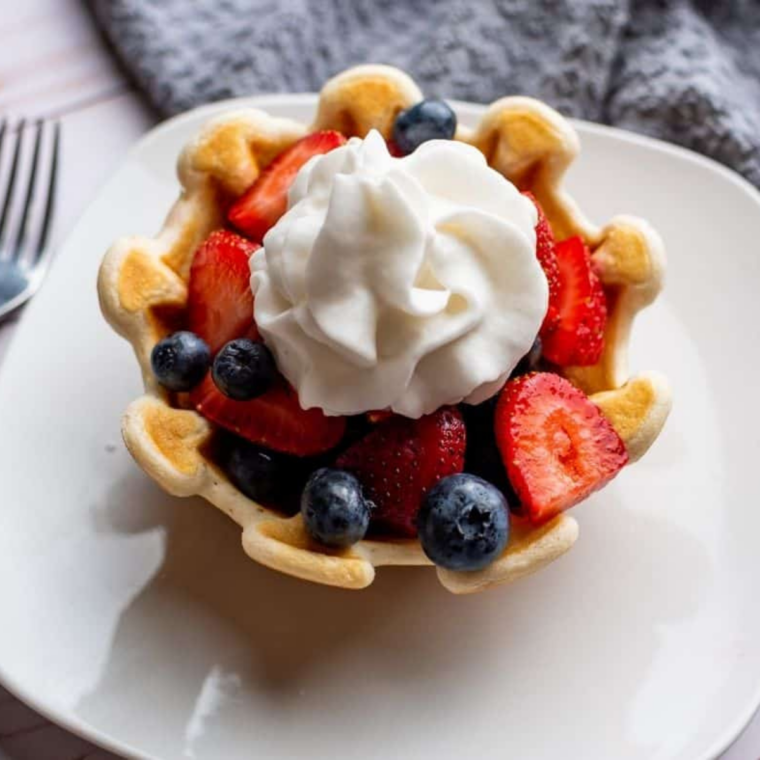 Crispy air fryer waffle bowl filled with whipped cream and fresh fruit on a plate