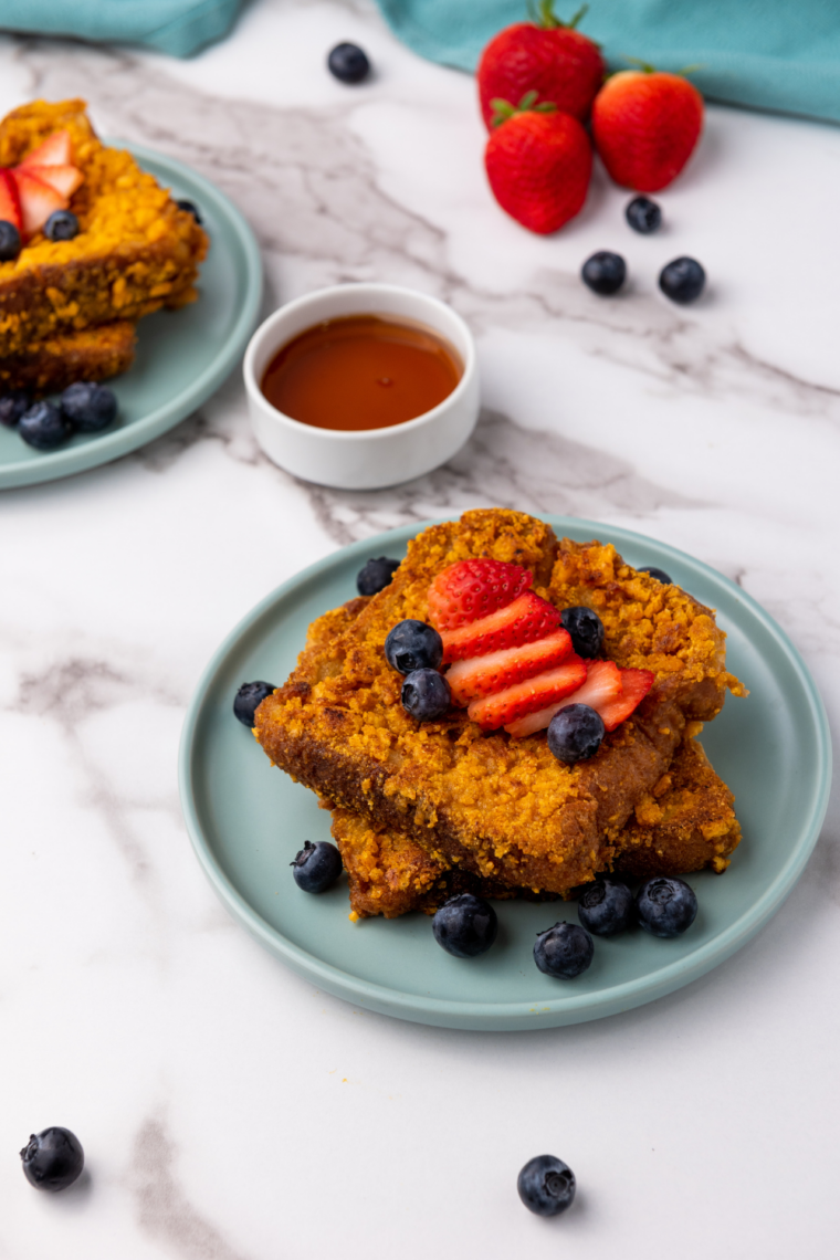 Air fryer Captain Crunch French toast slices, golden and crispy, served on a plate with syrup and fresh fruit
