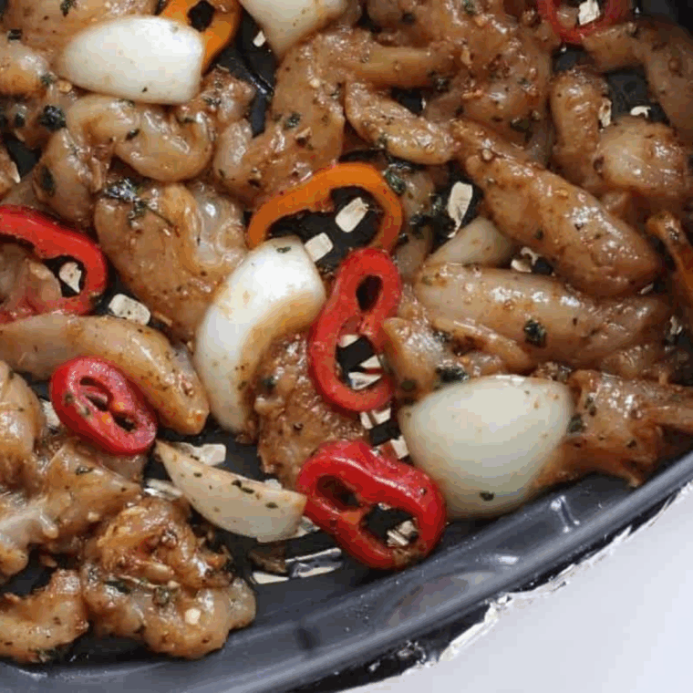 Diced chicken, bell peppers, and red onions tossed with taco seasoning, cooking in an air fryer