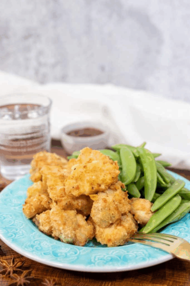 Air Fryer Chinese Chicken Fingers stacked on a plate, golden brown and crispy, served with dipping sauce.