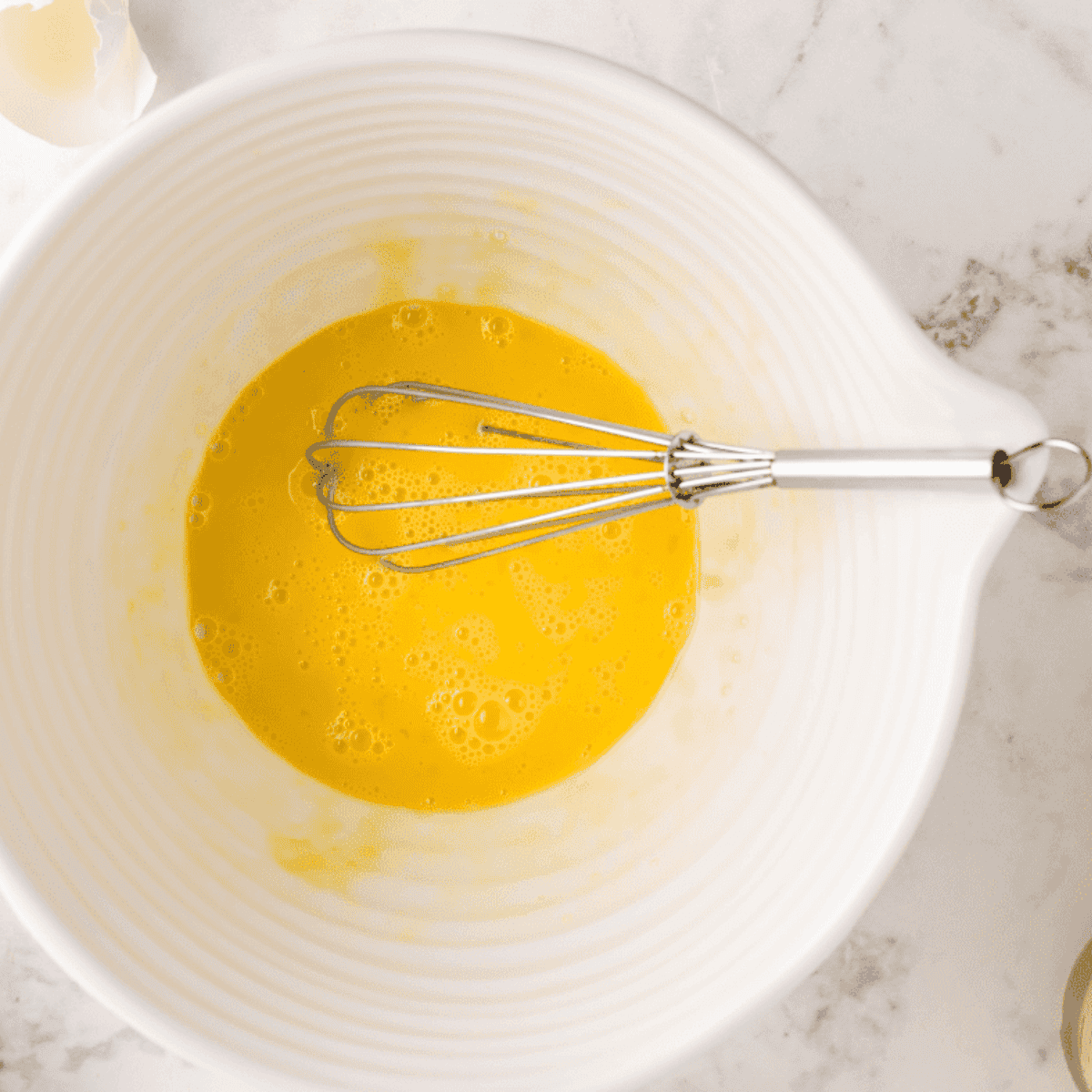 Whisking eggs, melted butter, vanilla, and chopped walnuts in a large mixing bowl