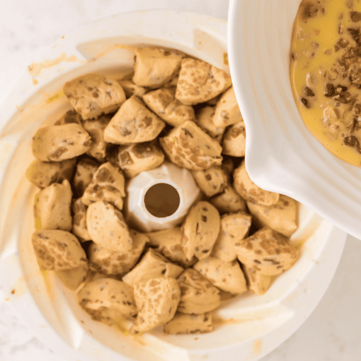 Cinnamon rolls in a Bundt pan coated with melted butter mixture and covered with foil