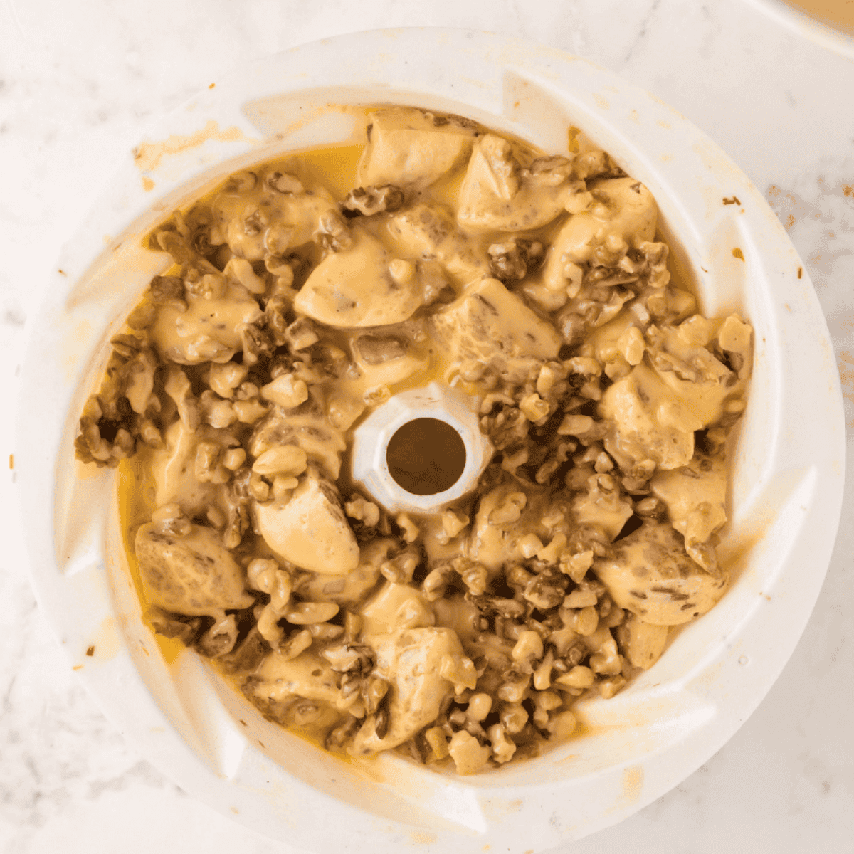 Bundt pan with cinnamon rolls cooking in the air fryer, foil removed for final browning