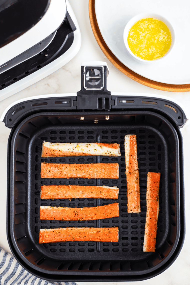 Seasoned imitation crab bites cooking in an air fryer basket until crispy and golden brown.