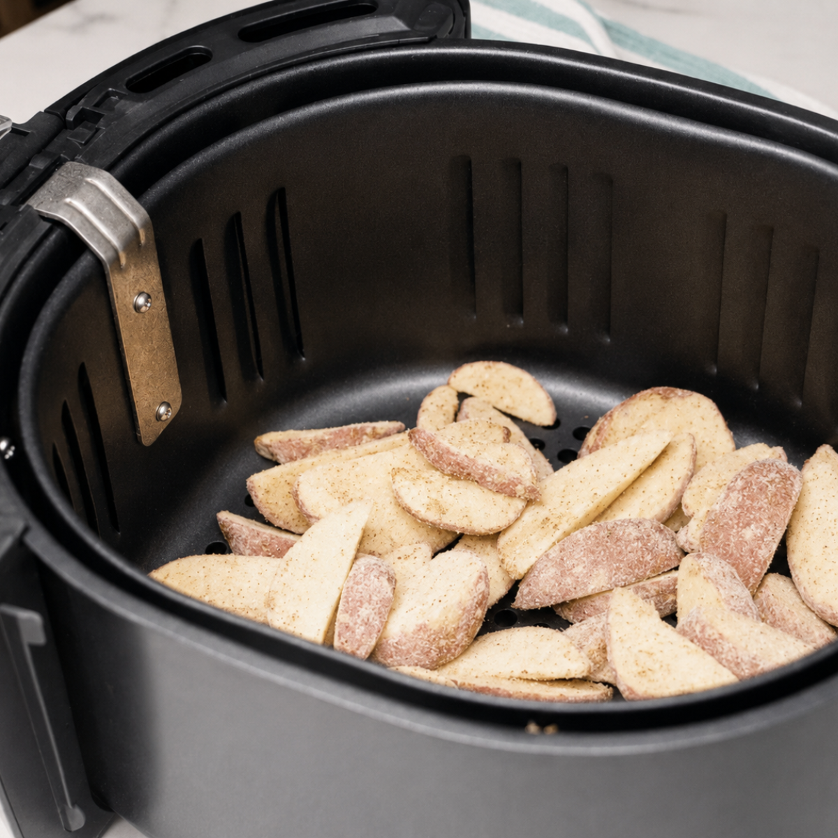 Frozen potato wedges arranged in a single layer in an air fryer basket before cooking