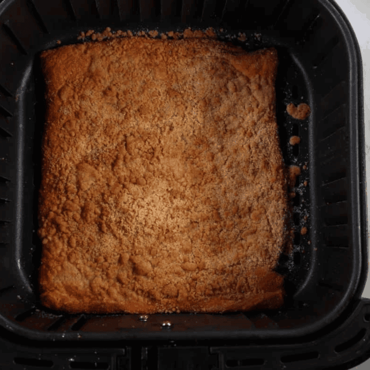 Cooked dough in the air fryer basket with cinnamon sugar coating on top.