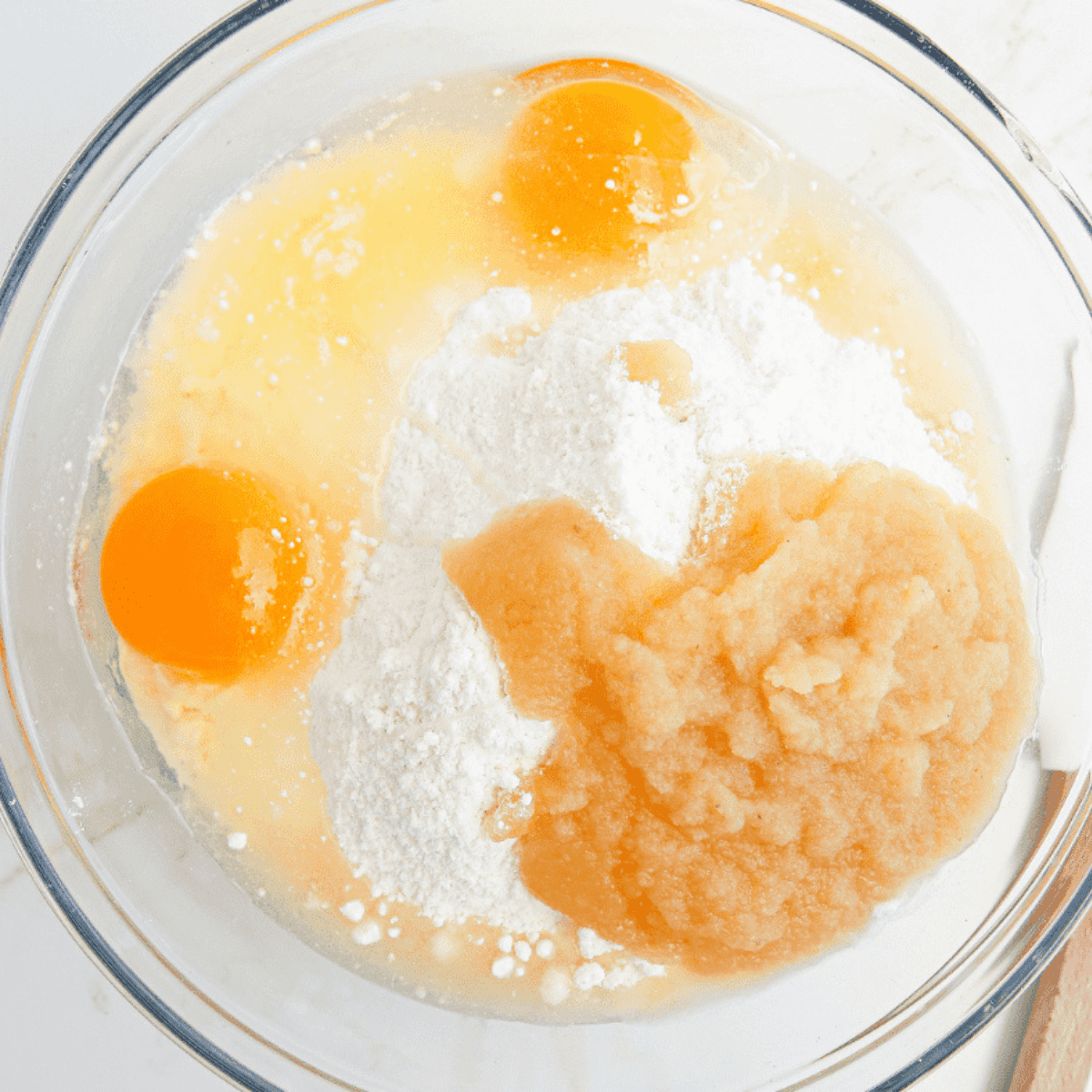 Whisking eggs, applesauce, melted butter, and vanilla extract until smooth