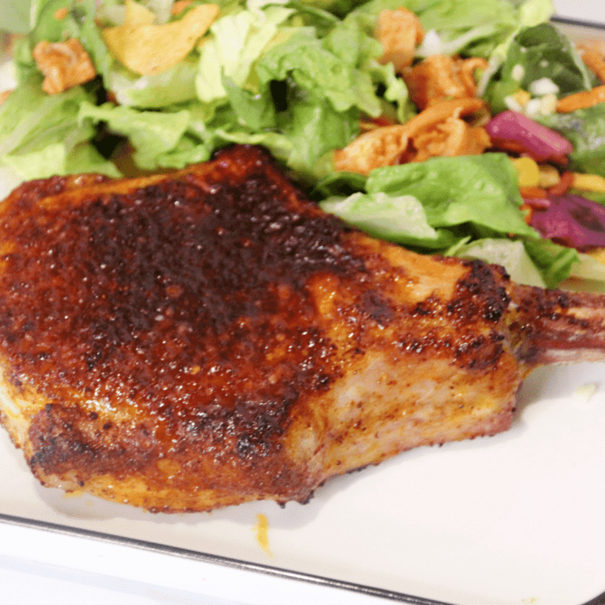 Juicy air fryer pork chop seasoned with chili lime and garnished with fresh lime slices.