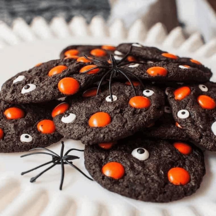 A batch of dark chocolate Halloween cookies with candy eyeballs cooling on a wire rack, showing a soft and chewy texture.