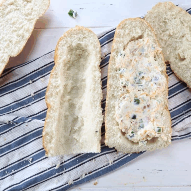 Filling hollowed bread with cheese, jalape&ntilde;o, and bacon mixture