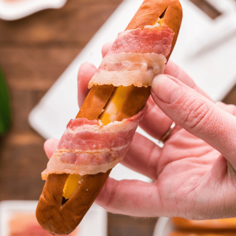 Bacon wrap step: Strip of pre-cooked bacon spiraled around a cheese-stuffed hot dog