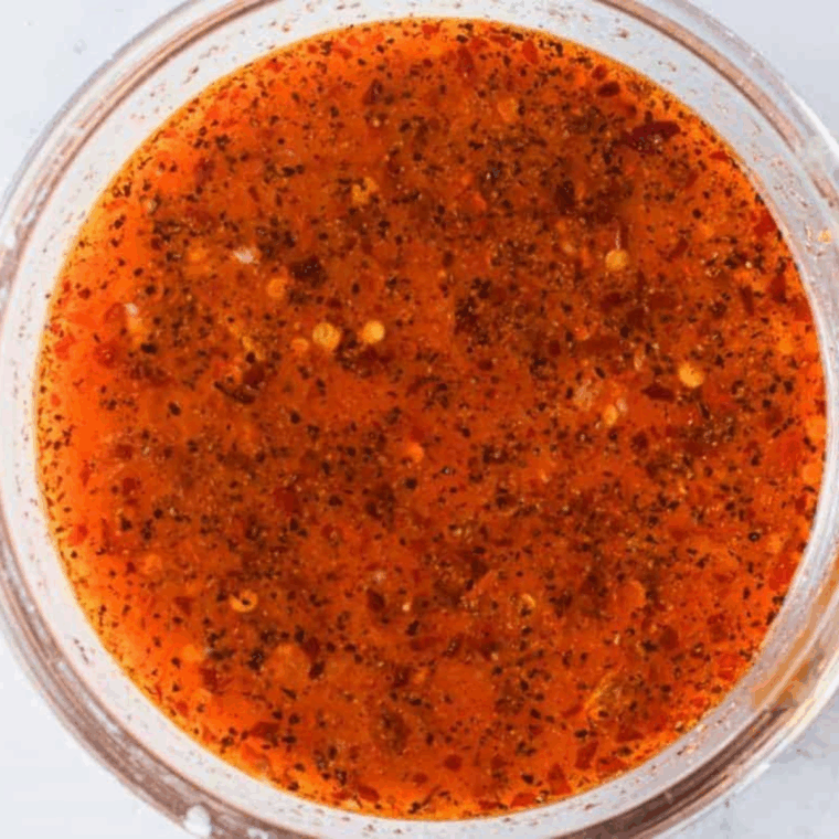 Tossing chicken wings in sweet chili sauce, garlic, and seasonings for coating.